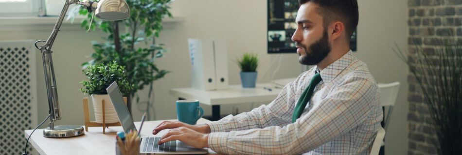 office worker sitting at a desk and working on a laptop