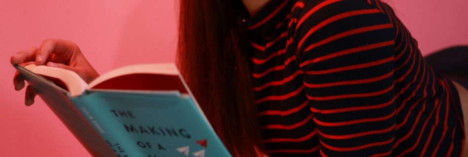 woman in striped long sleeve shirt holding a book